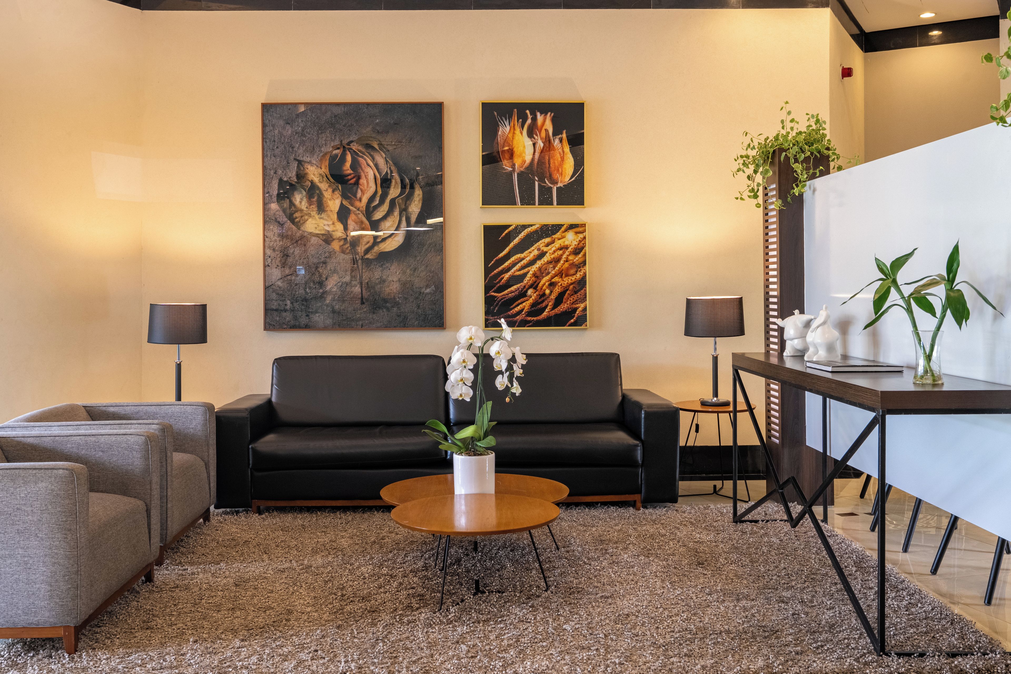 Ein modernes Wohnzimmer mit einem schwarzen Sofa, einem Couchtisch und zwei Bildern an der Wand.