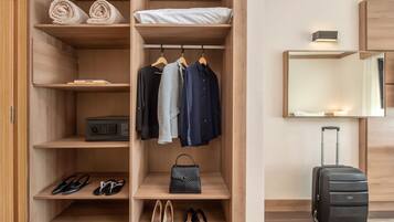 A wooden wardrobe with shelves for folded clothes, a hanging rack, and a suitcase.