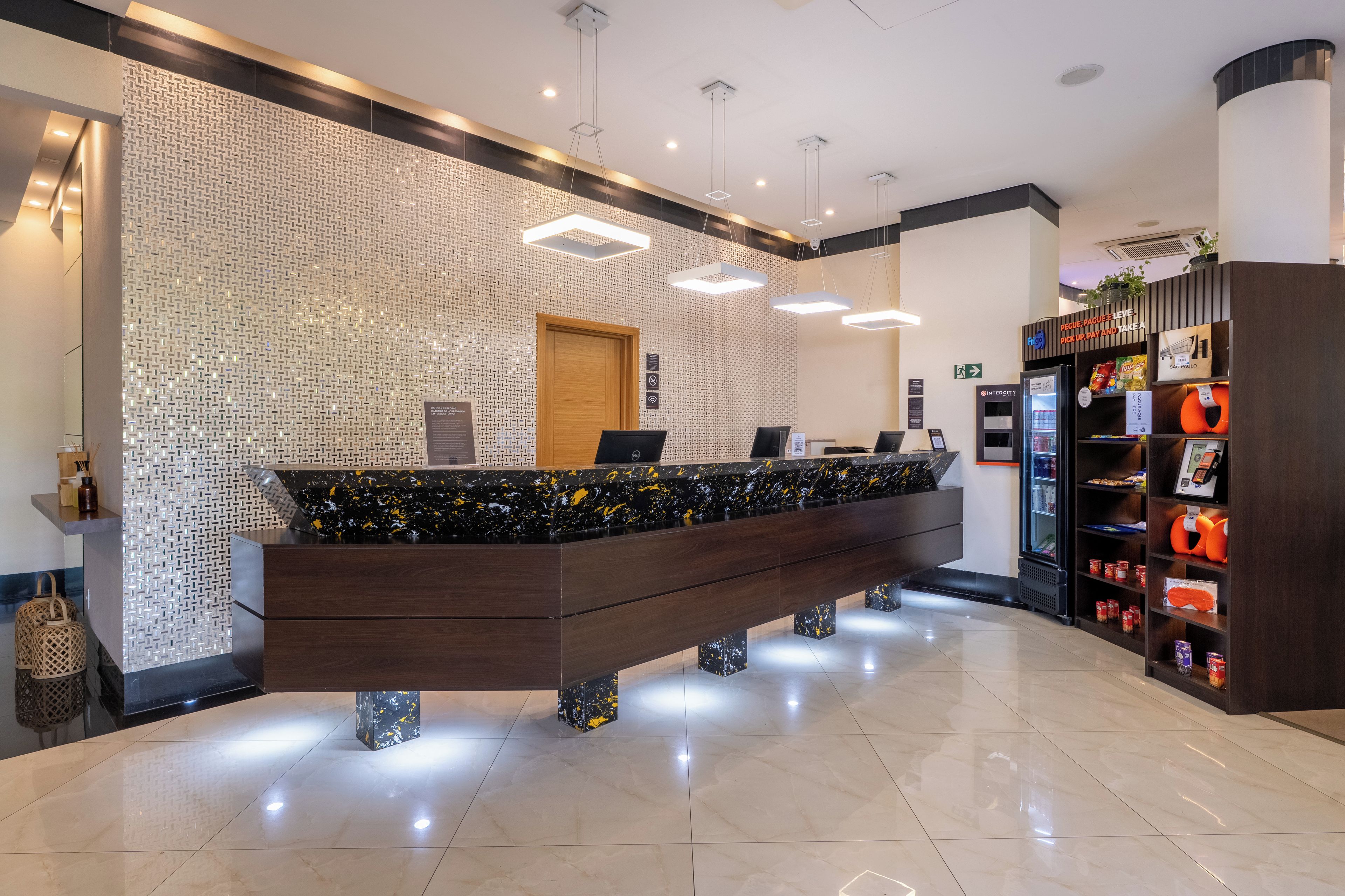 A reception desk with a patterned wall, a refrigerator, and a shelf with snacks.