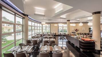 A spacious restaurant with large windows, modern lighting, and a buffet area.