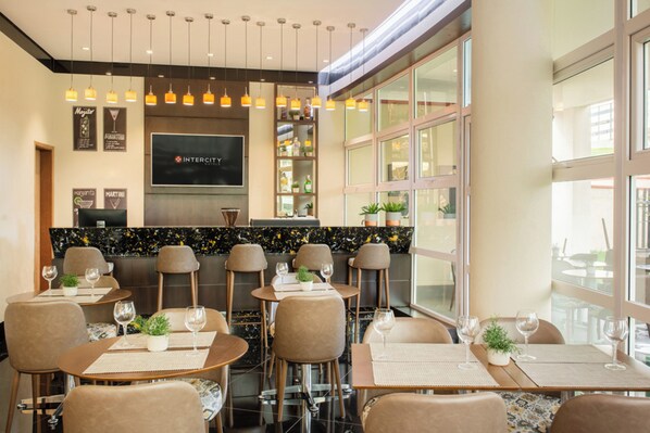A modern hotel lobby with a bar area, seating arrangements, and a large screen displaying the hotel name. - Intercity Itupeva (Itupeva)