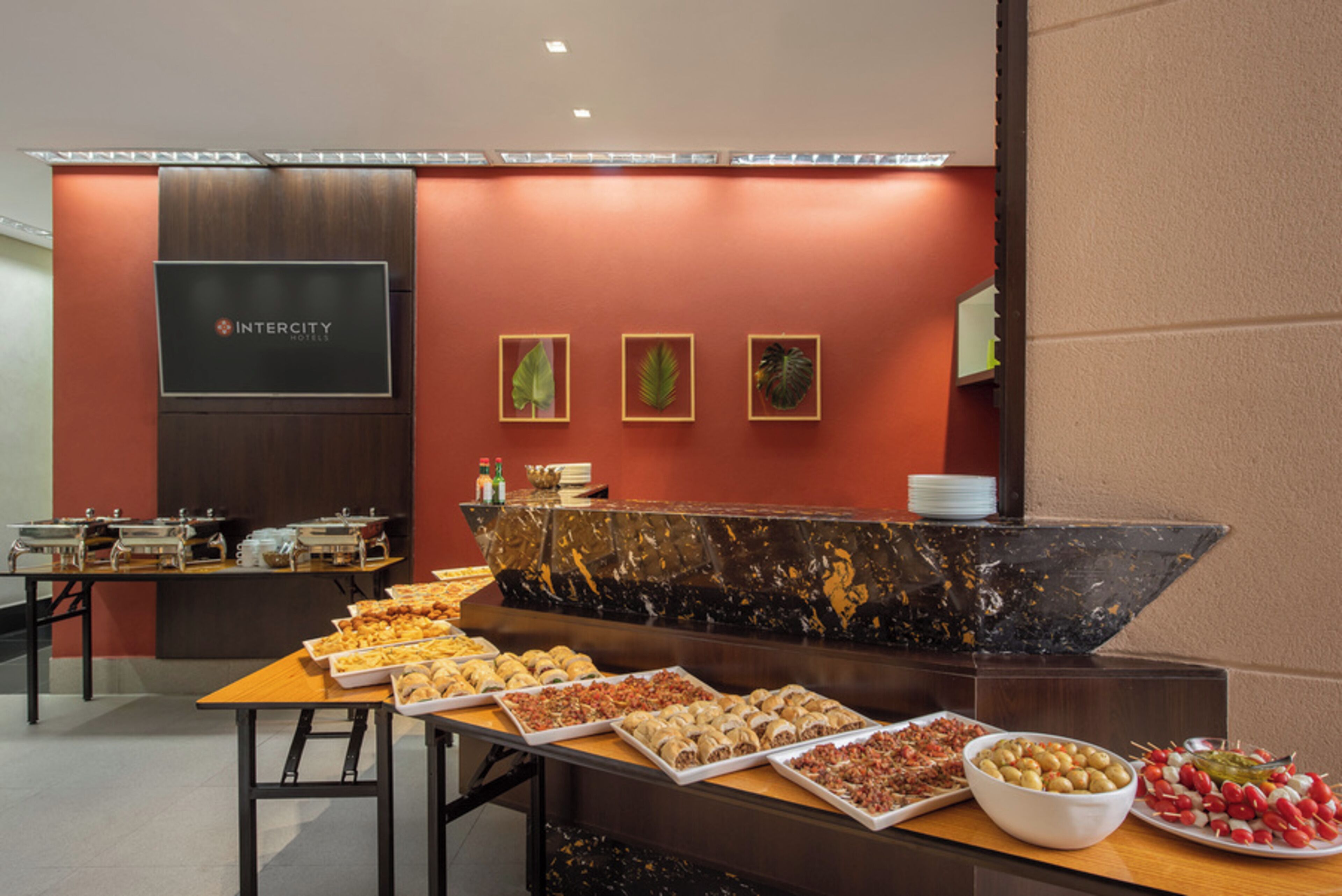 A buffet setup with various food items and a reception desk with the Intercity Hotels logo.