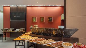 Montaje tipo bufé con diferentes opciones de comida y una recepción con el logotipo de Intercity Hotels.