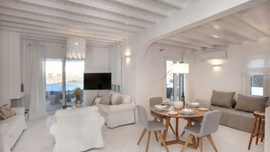 A spacious living area with a dining table, sofas, and a TV. - Mykonian house in Elia beach by GHH (Mykonos)