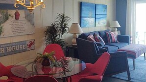En matplats med ett glasbord, röda stolar och en kristallkrona. I bakgrunden finns en soffa och en lampa.