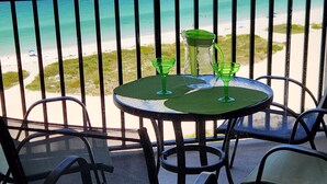 Un balcone con tavolo e sedie che si affaccia su una spiaggia.
