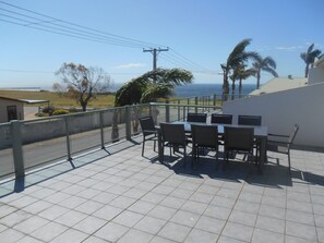A terrace with a table and chairs overlooking a coastal view. - Adam's View -     Off Peak Special! - Free WiFi (Ardrossan)