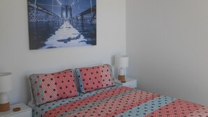 Et soveværelse med en seng, et natbord, en lampe og en loftsvifte.