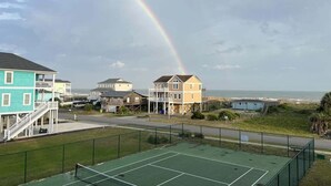 Un campo da tennis, case e un arcobaleno.