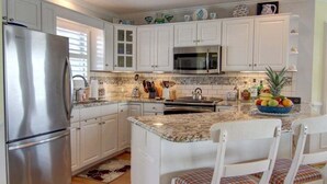 A kitchen with white cabinets, stainless steel appliances, a granite countertop, and a fruit bowl. - Turtle Cove is a spacious 4-bed home in Holden Beach, perfect for 9 guests. (Holden Beach)