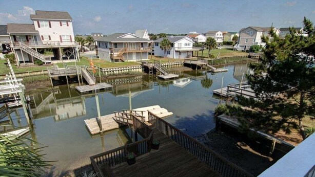 A residential area with houses, a dock, and a small water body. - Turtle Cove is a spacious 4-bed home in Holden Beach, perfect for 9 guests. (Holden Beach)