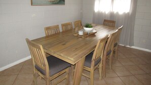 A dining area with a wooden table, six chairs, a white bowl with a plant, and a framed picture on the wall. - The Catch  ~ short walk to beach! Dog Friendly  - Off Peak Special! (Stansbury)