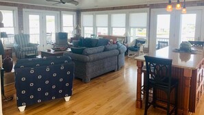 A spacious living area with a sofa, armchairs, a dining table, and a ceiling fan. - Experience luxury at Shore Beats Workin', a spacious 5BR retreat in Holden Beach. (Holden Beach)