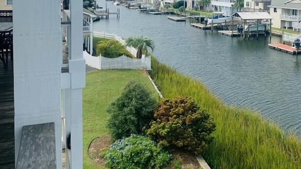 A riverside view with a dock, boats, and residential buildings. - Experience luxury at Shore Beats Workin', a spacious 5BR retreat in Holden Beach. (Holden Beach)