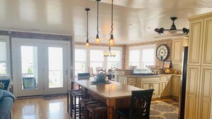 A spacious kitchen with a large island, wooden chairs, and pendant lighting. - Experience luxury at Shore Beats Workin', a spacious 5BR retreat in Holden Beach. (Holden Beach)