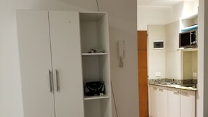 Ein Zimmer mit einem weißen Kleiderschrank, einer Mikrowelle und einem Waschbecken.