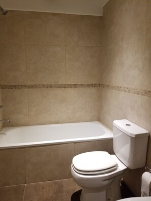 A bathroom with a bathtub, toilet, and shower. - Studio Bulnes (Buenos Aires)