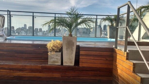 Eine Dachterrasse mit Blick auf eine Stadtlandschaft, einem Pool und Holzstufen.