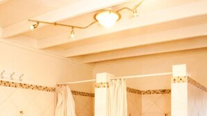 Un baño con tres cabinas de ducha, cada una con cortina, banco y suelo de baldosas.