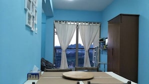 A dining area with a table and chairs, a window with curtains, and a view of the outside. - Triple B's Staycation - Simple and Comfy (Petaling Jaya)