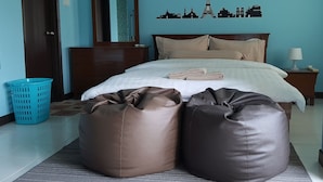 A bedroom with a bed, a dresser, a mirror, a wall with a cityscape mural, and two bean bags. - Triple B's Staycation - Simple and Comfy (Petaling Jaya)