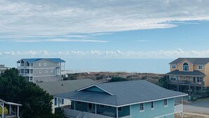 Ett bostadsområde vid kusten med hus, en strand i bakgrunden och en klar himmel.