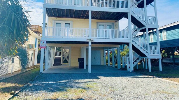 En byggnad med flera våningar, en inglasad veranda och en trappa som leder upp till de övre våningarna.
