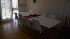 Un coin repas avec une table blanche, six chaises et une décoration centrale rouge.