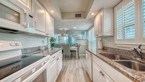 Una cocina con encimeras de granito, armarios blancos y una isla central.