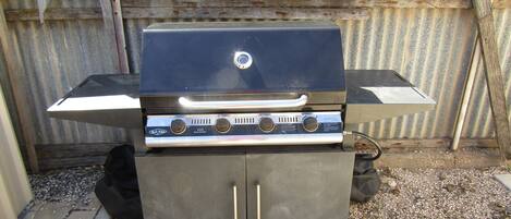 Una parrilla para barbacoa con panel de control, un armario de almacenamiento y una rejilla metálica.