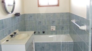Een badkamer met een bad, een wastafel en een spiegel.