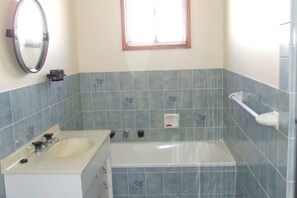 A bathroom with a bathtub, a sink, and a mirror. - Government Rd 63 - Shoal Bay (Shoal Bay)