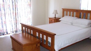 Een slaapkamer met een houten bed, een nachtkastje en een lamp.