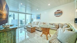 A modern living room with a sofa, a glass coffee table, and a wicker chair. - LaPlaya 102E-Tropical garden view near the pool! (Longboat Key)