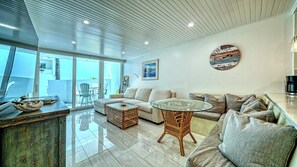 A modern living room with a sofa, a glass coffee table, and a wicker chair.