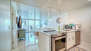 Una cocina moderna con una isla central, horno integrado y un comedor con sofá y sillas.