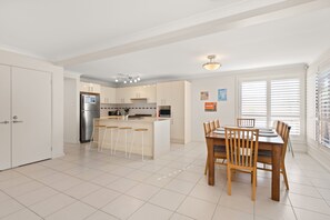 Una cucina moderna con isola centrale, sgabelli da bar e tavolo da pranzo con sedie.