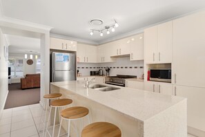 Una cucina moderna con isola centrale, elettrodomestici in acciaio inossidabile e sgabelli da bar.