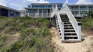 Ein Strandgrundstück mit einer Treppe, die zu einem Balkon führt, umgeben von Vegetation.