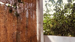 A covered outdoor area with a woven wall, a tire bench, and a concrete floor.