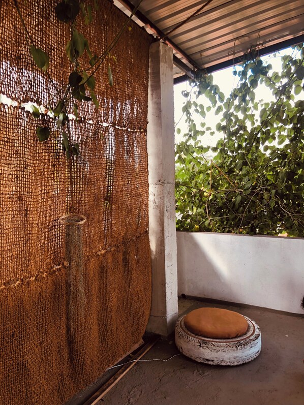 A covered outdoor area with a woven wall, a tire bench, and a concrete floor.