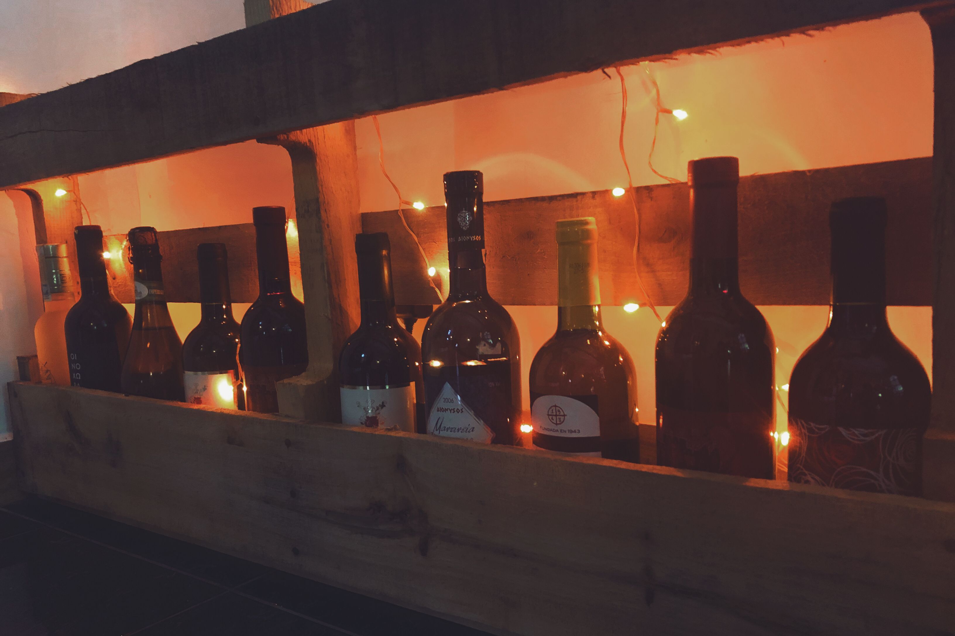 A wooden display case containing several bottles of wine, illuminated by warm lighting.