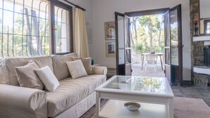 Una sala de estar con un sofá color beige, una mesa de centro de vidrio y vistas a un patio exterior con una mesa y sillas.