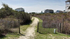 A gravel path leading to a gated area with houses in the background.