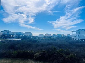 Une zone résidentielle côtière, avec des maisons, dont certaines sont surélevées, sous un ciel dégagé.