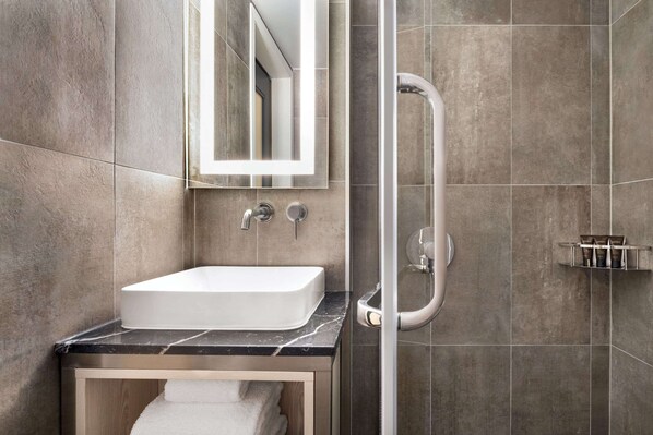 Un baño moderno con lavamanos blanco, un espejo y ducha.
