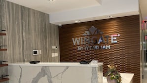 A reception desk with a marble top and a wooden panel wall behind it.