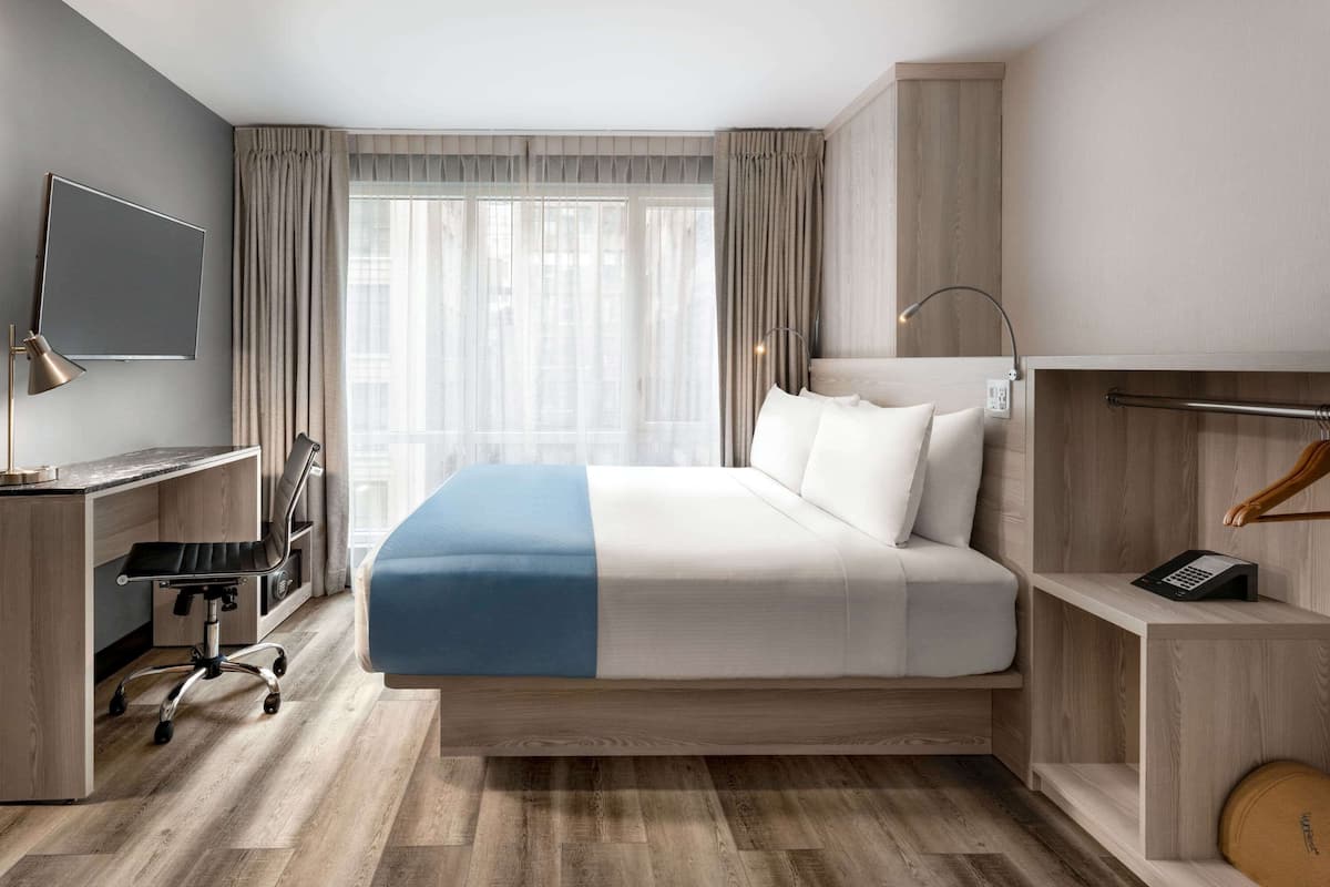 Une chambre d’hôtel équipée d’un lit, d’un bureau, d’une chaise et d’un téléviseur.