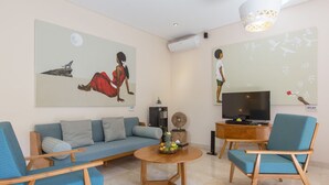 En moderne stue med sofa, to lænestole, sofabord, fjernsyn og kunst på væggene.