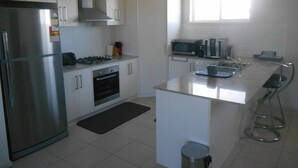 A modern kitchen with white cabinets, stainless steel appliances, a gas stove, a microwave, and a window providing natural light. - The White House ~ Free Wi-Fi, Arcade Machine - Off Peak Special! (Edithburgh)